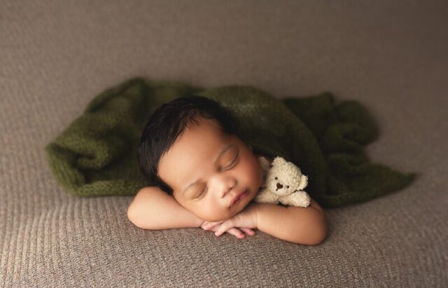 Newborn baby posed in neutral tones with soft green accents during a studio session by a CT newborn photographer
