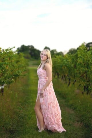 Connecticut high school senior photography session at Gouveia Vineyards in Wallingford CT, senior girl wearing a pink dress posing among vineyard rows.