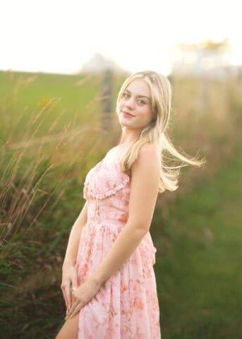 Connecticut high school senior photography session at Gouveia Vineyards in Wallingford CT, senior girl wearing a pink dress posing among vineyard rows.