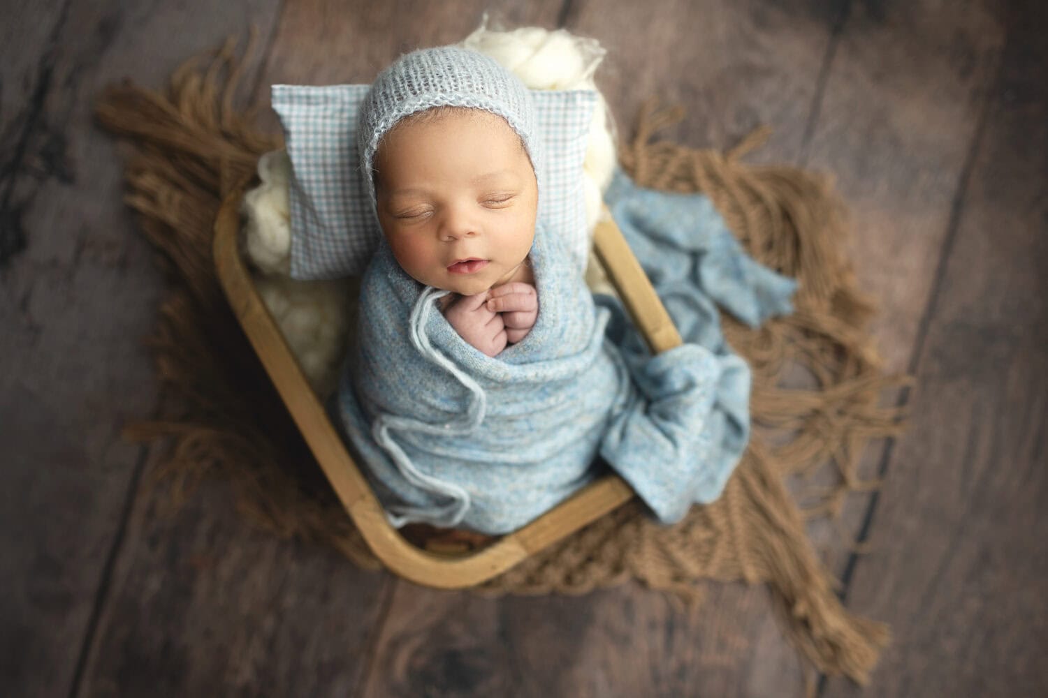Newborn baby boy posed in soft blues in a basket by CT newborn photographer Elizabeth Frederick Photography